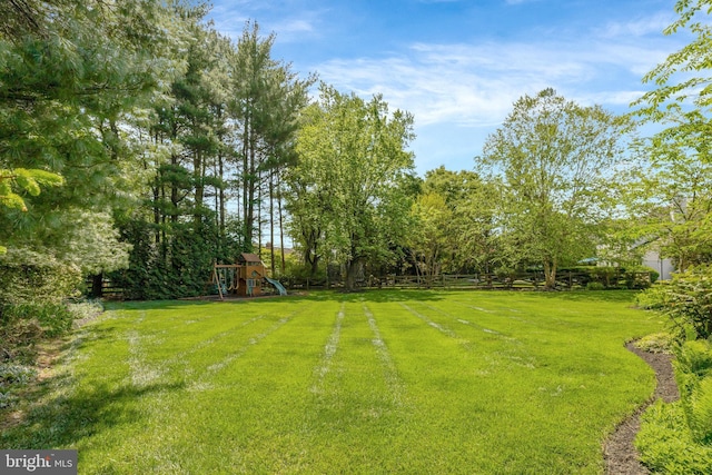 view of yard featuring playground community and fence