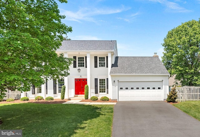 greek revival house featuring fence, an attached garage, driveway, and a front yard