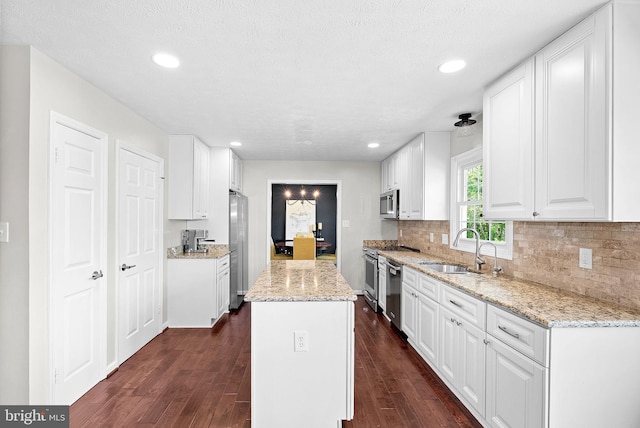 kitchen featuring white cabinets, a sink, stainless steel appliances, tasteful backsplash, and dark wood-type flooring