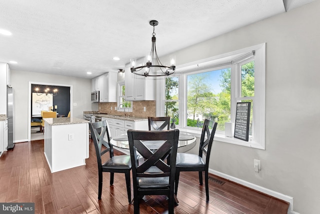dining room featuring baseboards, a textured ceiling, a chandelier, and dark wood-style floors