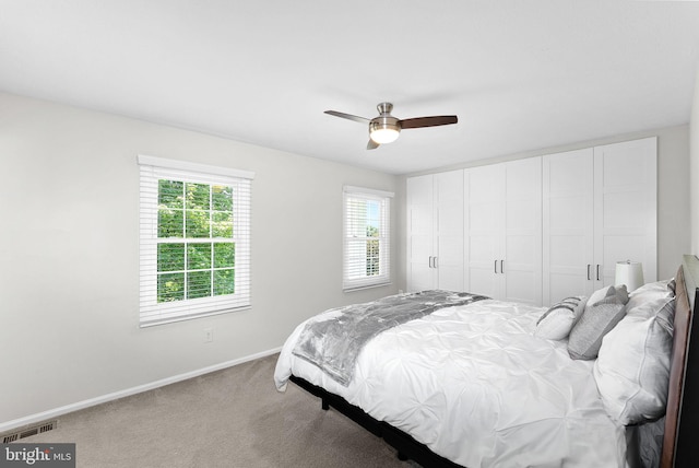 carpeted bedroom featuring baseboards, a ceiling fan, and visible vents