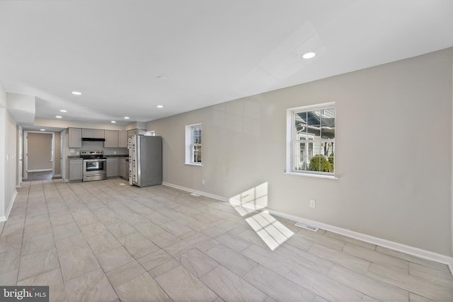unfurnished living room featuring plenty of natural light, baseboards, and recessed lighting