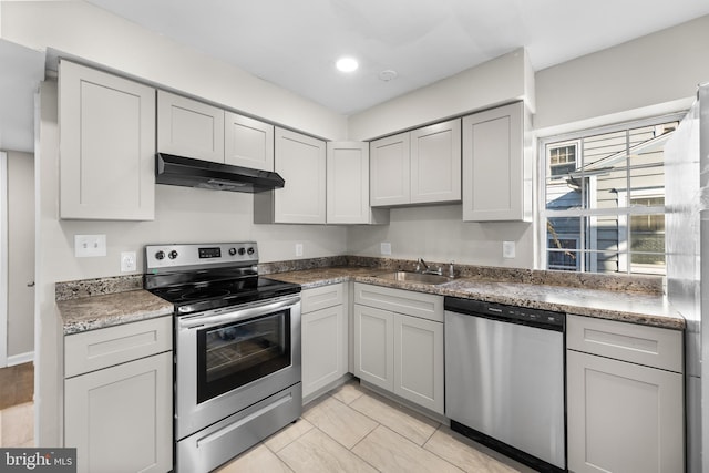 kitchen with appliances with stainless steel finishes, under cabinet range hood, a sink, gray cabinetry, and recessed lighting
