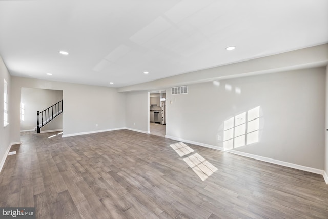 unfurnished living room with baseboards, recessed lighting, wood finished floors, and stairs