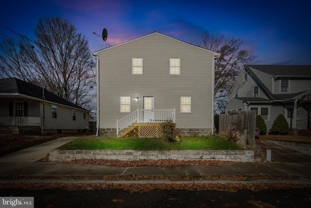 back of house at dusk featuring fence