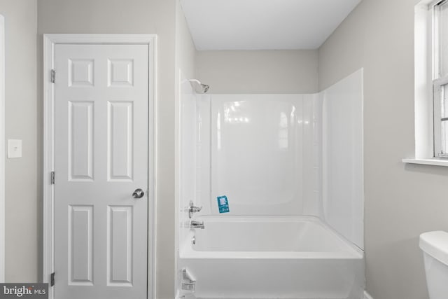 full bathroom with bathing tub / shower combination, toilet, and baseboards
