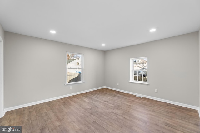 empty room featuring wood finished floors, baseboards, and recessed lighting