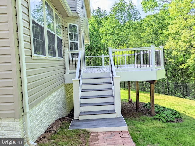 wooden terrace featuring a yard, fence, and stairs