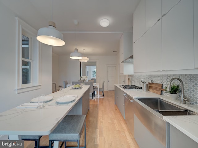 27 Seaton Pl NW, Washington, DC 20001 - kitchen with light stone countertops, a sink, light wood-style floors, pendant lighting, and modern cabinets