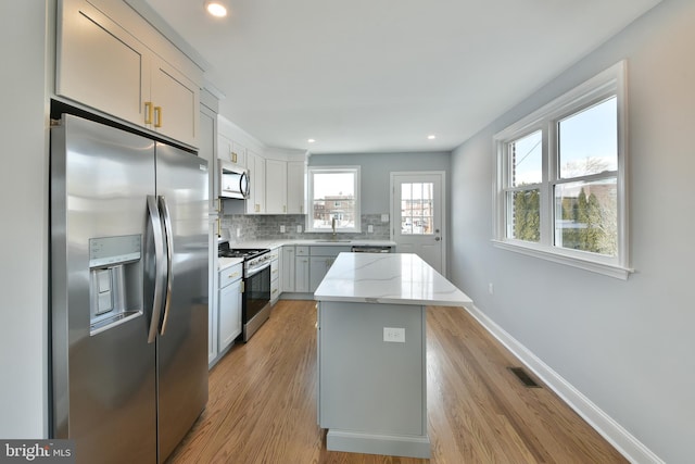 kitchen featuring decorative backsplash, visible vents, appliances with stainless steel finishes, baseboards, and light stone counters