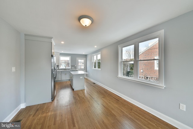 kitchen with light countertops, baseboards, freestanding refrigerator, and wood finished floors