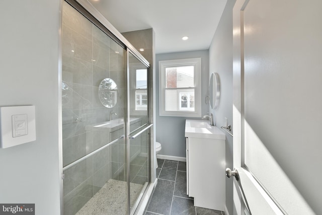 bathroom with vanity, baseboards, a stall shower, and toilet