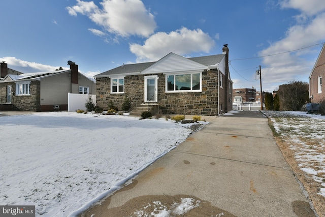 view of front of house with a chimney, stone siding, and concrete driveway