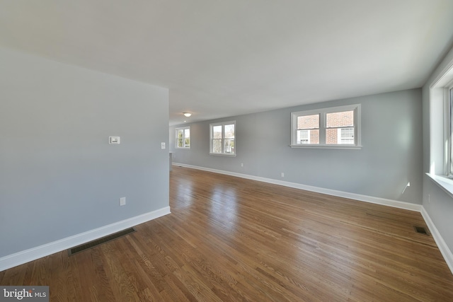 spare room with baseboards, visible vents, and wood finished floors
