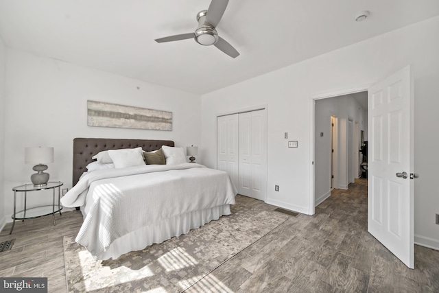 bedroom with ceiling fan, baseboards, wood finished floors, visible vents, and a closet