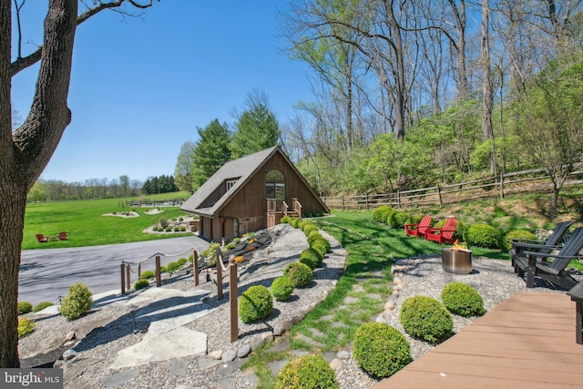 exterior space featuring an outdoor structure, a garage, an outdoor fire pit, and fence