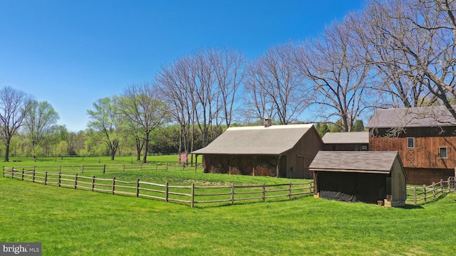 view of yard featuring a barn, an outdoor structure, and fence
