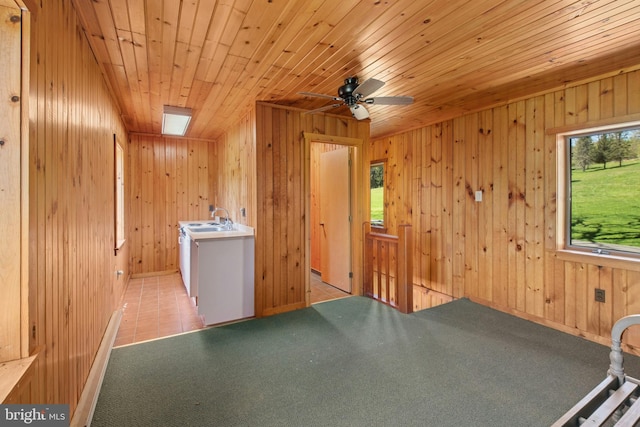 interior space with wood ceiling, a ceiling fan, a sink, wooden walls, and carpet