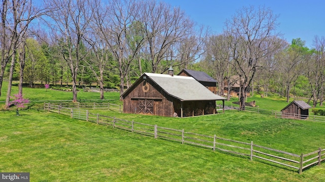 view of side of property with a yard, a barn, and an outbuilding