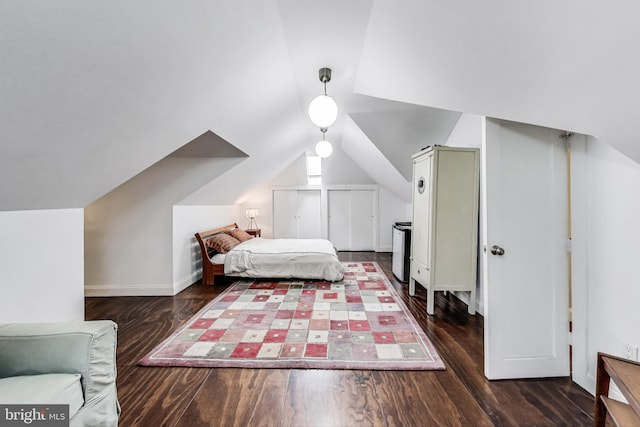 bedroom with baseboards, wood finished floors, and vaulted ceiling