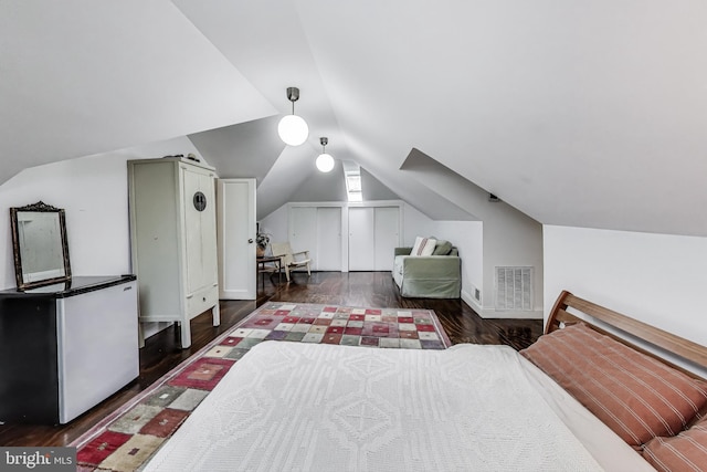 bedroom featuring lofted ceiling, refrigerator, wood finished floors, and visible vents