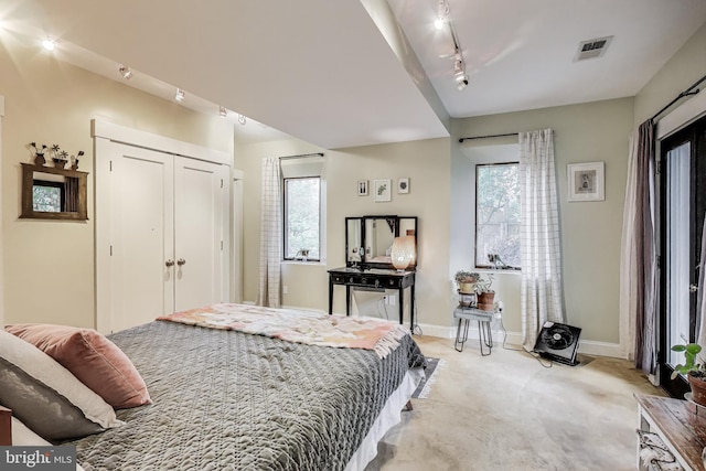bedroom featuring visible vents, a closet, light carpet, baseboards, and rail lighting