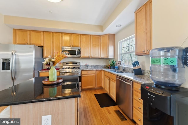12815 Duck Pond Dr Unit 111, Germantown, MD 20874 - kitchen with light wood-style floors, a center island, dark stone counters, a sink, and appliances with stainless steel finishes