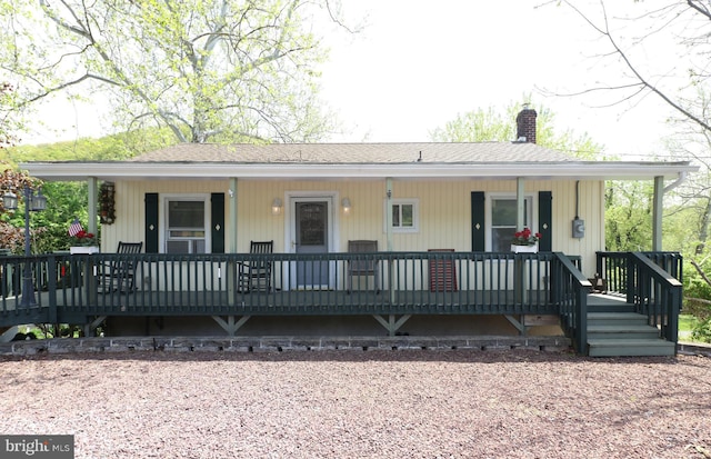 view of front of home featuring roof with shingles, covered porch, and a chimney
