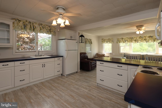kitchen with a ceiling fan, dark countertops, a sink, freestanding refrigerator, and ornamental molding