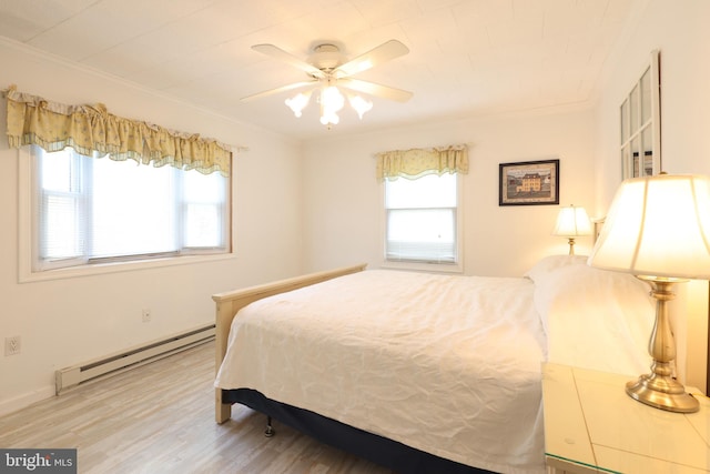 bedroom featuring crown molding, a baseboard heating unit, multiple windows, and wood finished floors