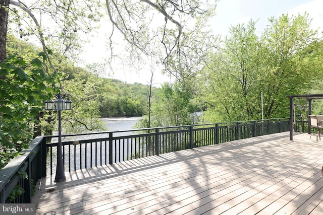 wooden terrace featuring a water view and a forest view