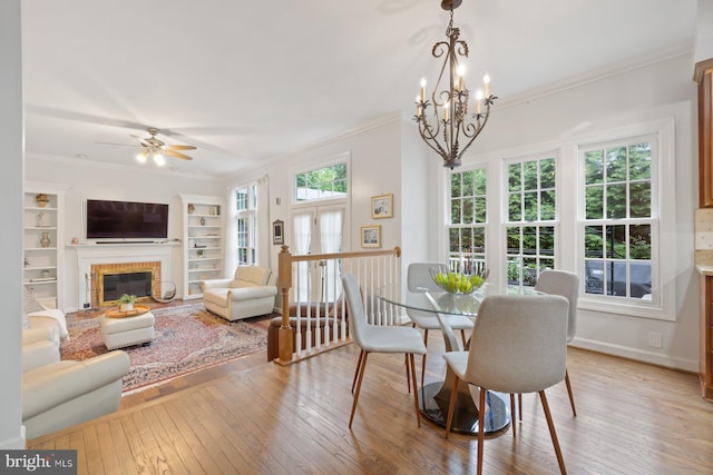 11406 Royal Vw, North Potomac, MD 20878 - dining room featuring light wood-type flooring, crown molding, a ceiling fan, a chandelier, and a fireplace