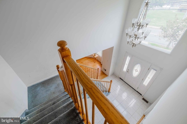entrance foyer with an inviting chandelier, a towering ceiling, light tile patterned floors, and visible vents
