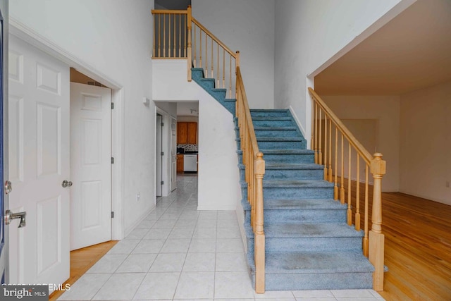 stairway featuring tile patterned flooring and a high ceiling