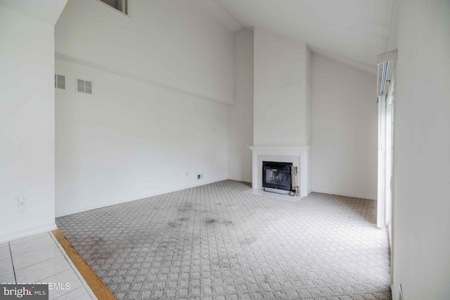 unfurnished living room featuring carpet floors, high vaulted ceiling, visible vents, and a fireplace with flush hearth
