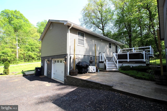 exterior space with an attached garage, aphalt driveway, and a deck