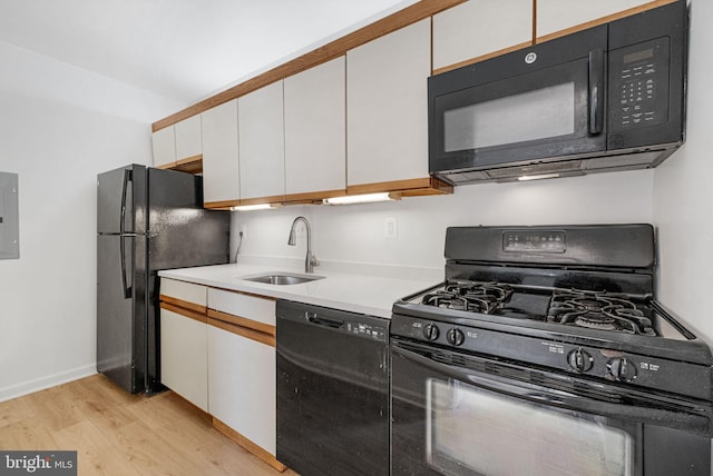 kitchen with light wood-style floors, light countertops, white cabinets, a sink, and black appliances