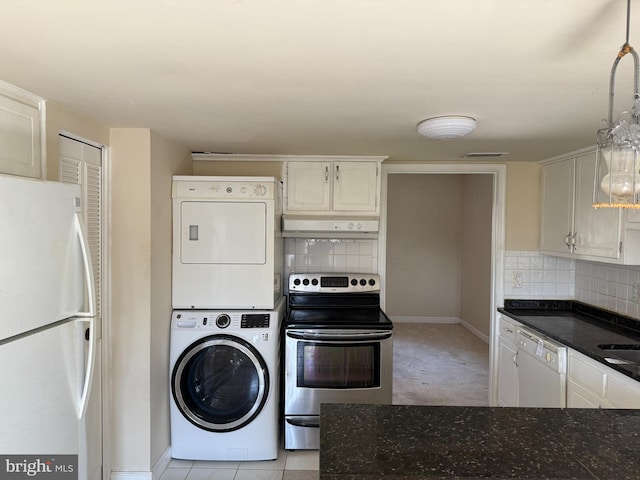 kitchen with white appliances, baseboards, stacked washer and clothes dryer, and tasteful backsplash