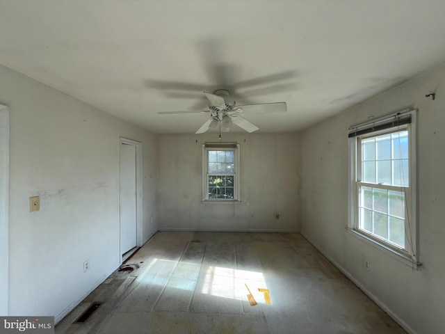 empty room featuring ceiling fan, visible vents, and baseboards