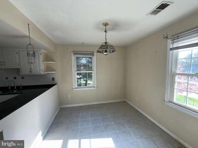unfurnished dining area featuring a sink, baseboards, light tile patterned flooring, and visible vents