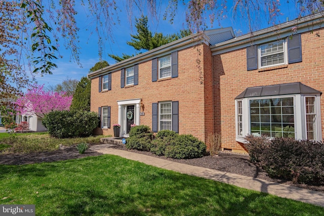 colonial home with brick siding and a front lawn