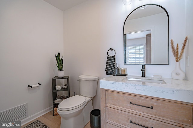 bathroom featuring visible vents, vanity, wood finished floors, toilet, and baseboards