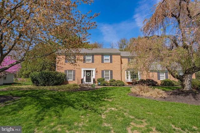colonial house with brick siding and a front yard