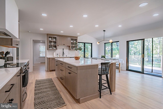kitchen with a kitchen island, stainless steel electric range oven, extractor fan, glass insert cabinets, and light wood-style flooring