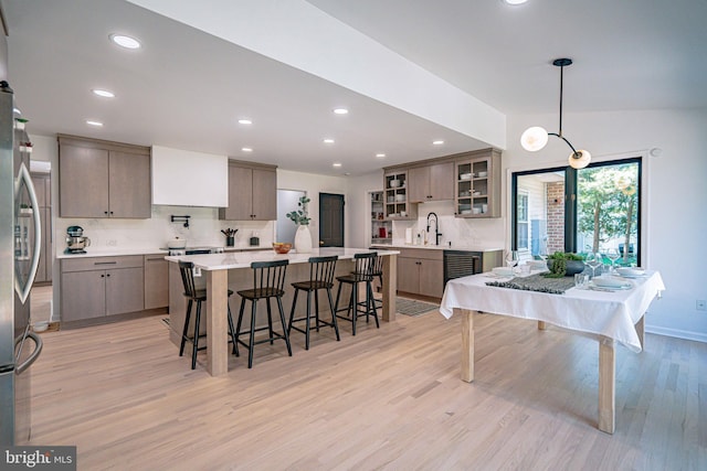 kitchen featuring recessed lighting, light wood finished floors, a breakfast bar area, and tasteful backsplash