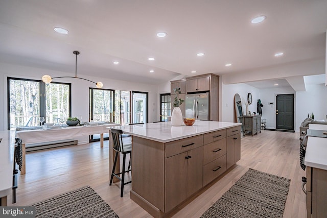 kitchen featuring light wood finished floors, a center island, freestanding refrigerator, open floor plan, and a baseboard radiator