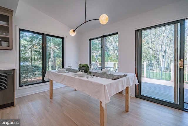 dining room with baseboards, light wood finished floors, and lofted ceiling