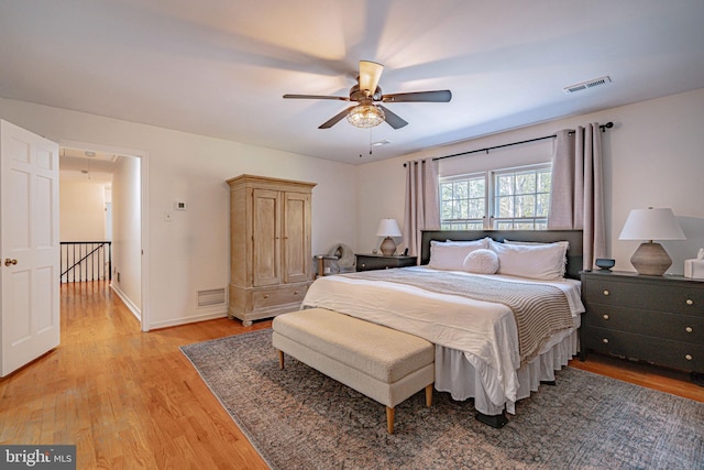 bedroom featuring light wood-style floors, baseboards, a ceiling fan, and visible vents