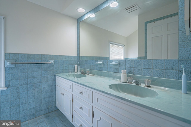 full bath with tile walls, visible vents, and a sink