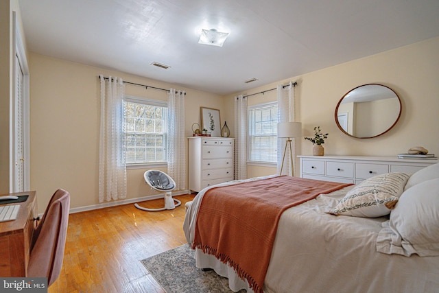 bedroom with visible vents, light wood finished floors, baseboards, and multiple windows
